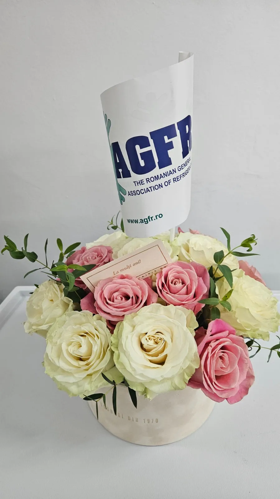 Aranjament floral cu trandafiri albi și roz, cu stegulețul AGFR și felicitarea „La mulți ani!”, la aniversarea a 35 de ani